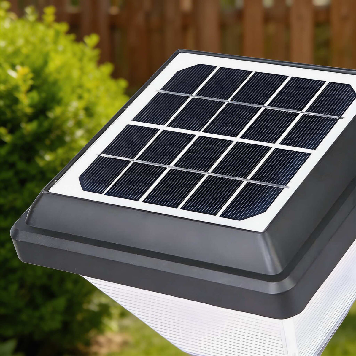 Close-up of the Joyo Solar Garden Light solar panel and frosted square shade in a garden bed