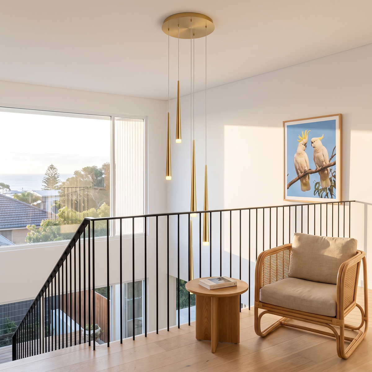 Gold six-light Jundaru cluster pendant in a coastal mezzanine void beside a rattan armchair