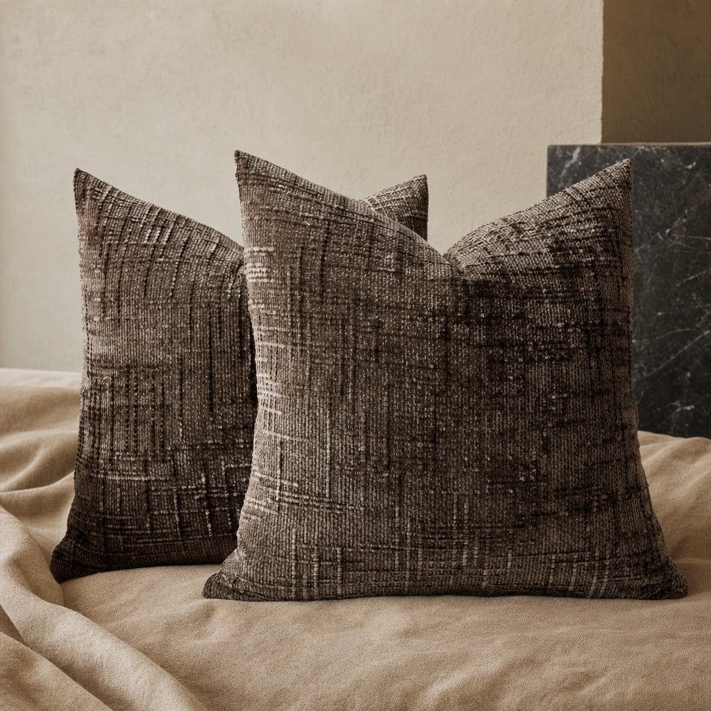 Pair of Lucina chenille throw pillows in a dark taupe tone on a sofa with a knit throw
