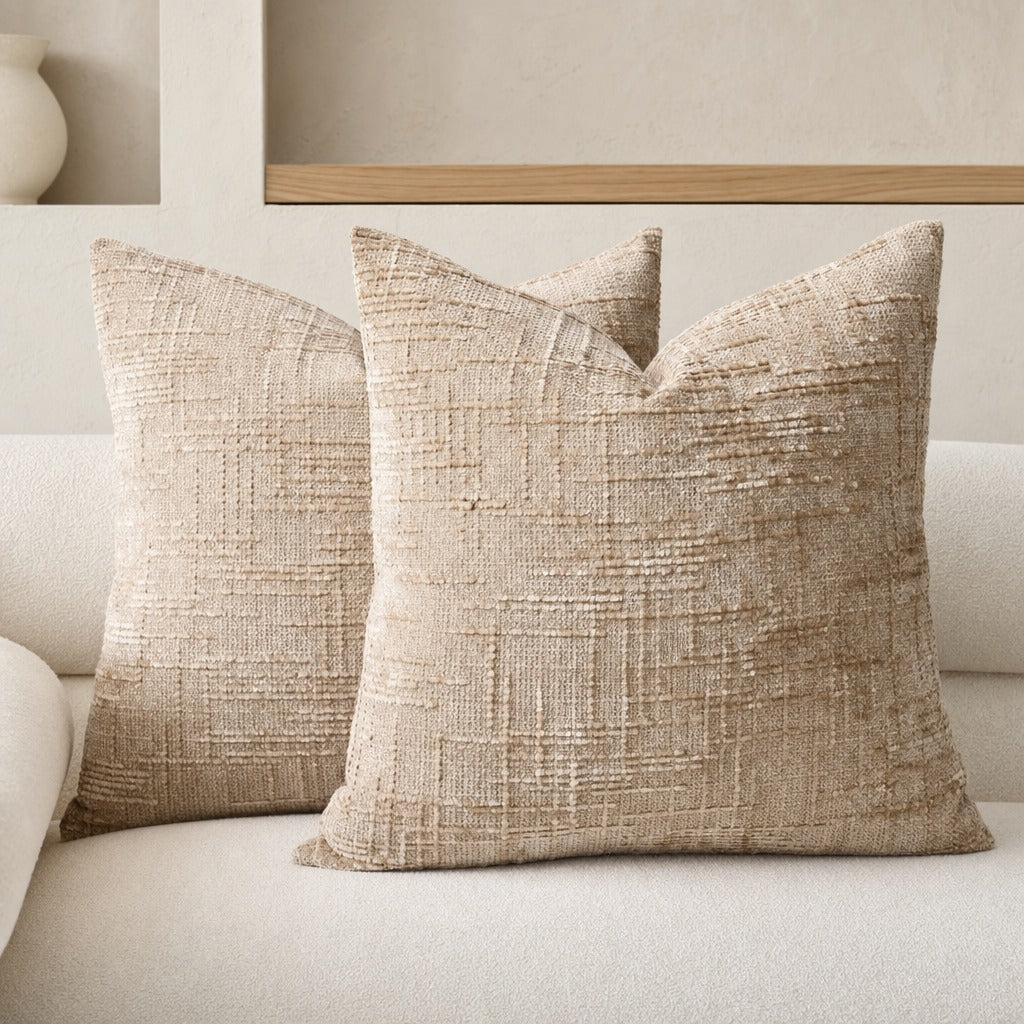 Lucina chenille throw pillows in light brown on a cream sofa below a timber shelf