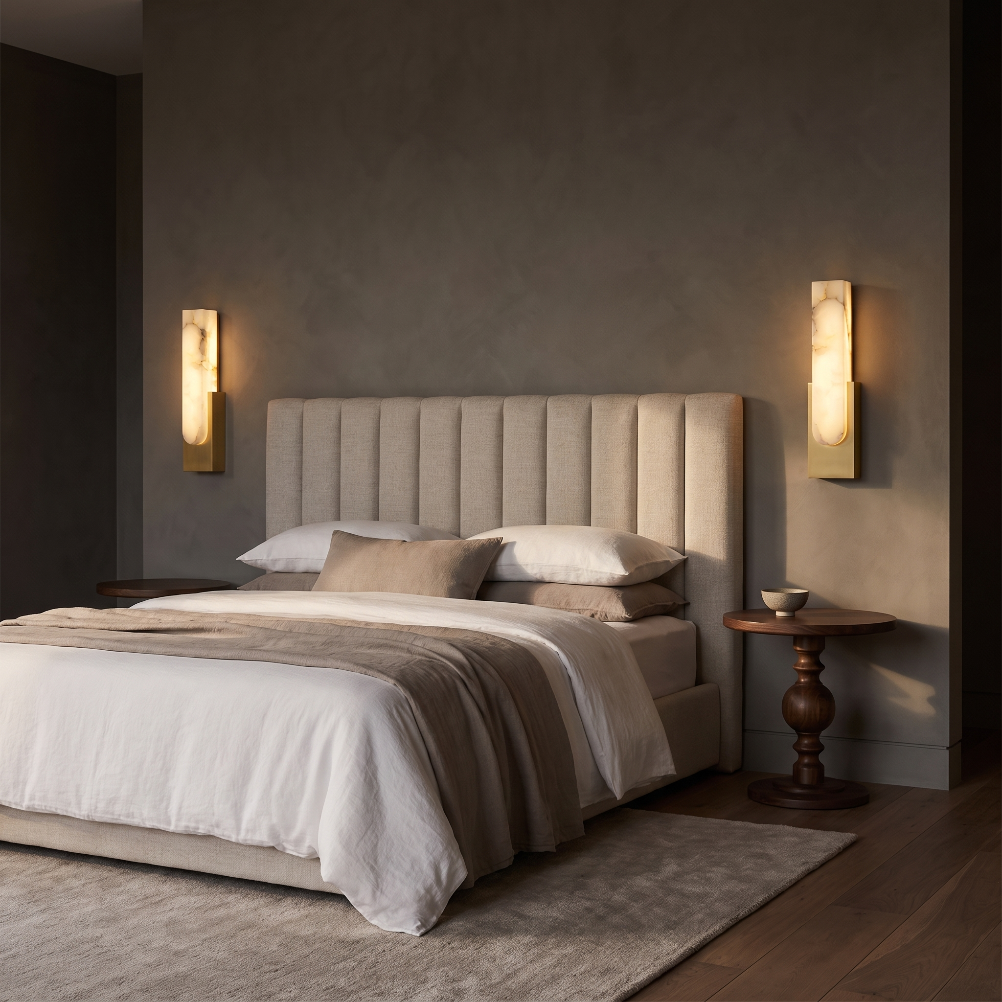 Pair of Mali alabaster LED wall sconces in Gold either side of a linen upholstered headboard