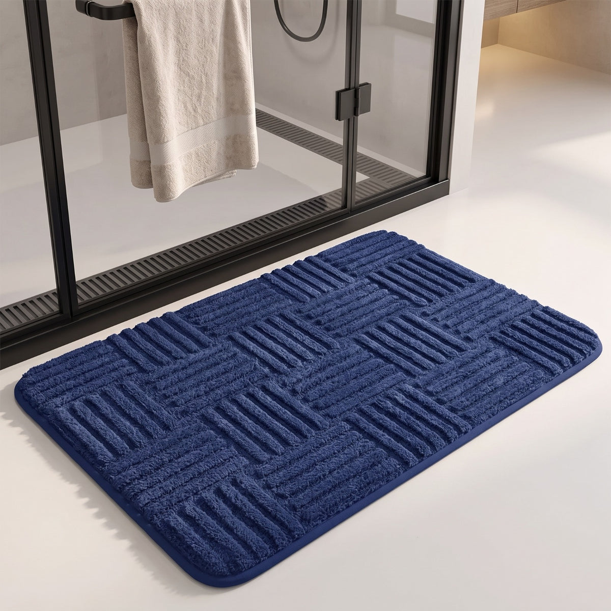 Marden striped non-slip bath mat in blue on a white floor in front of a glass shower