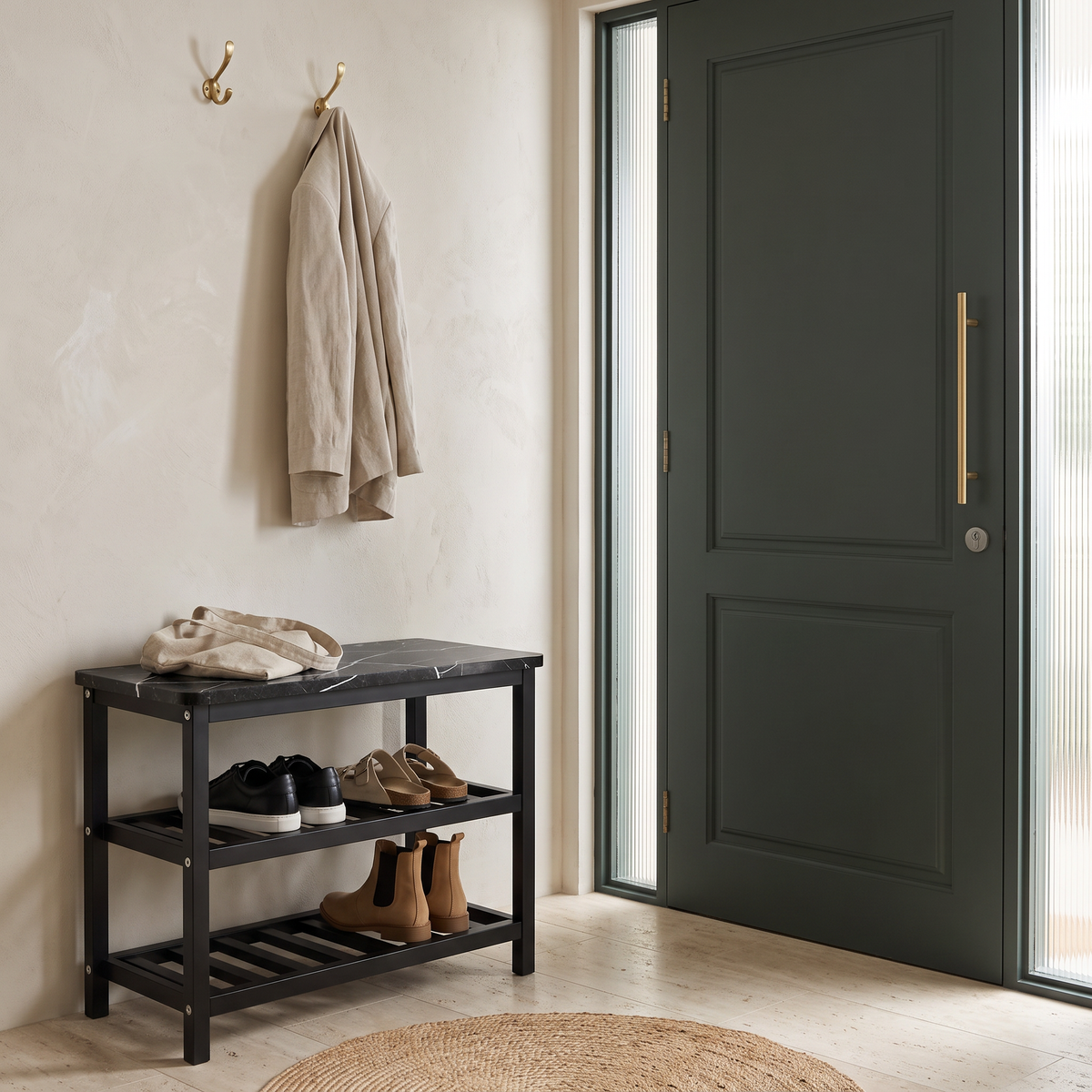 Mata shoe rack beside a charcoal green front door with a linen coat on brass wall hooks