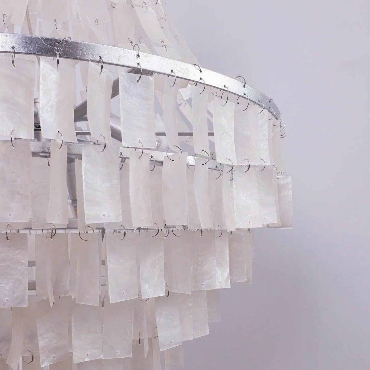 Close view of the Maui chandelier unlit, showing shell tiles hung on wire clips from the chrome rings