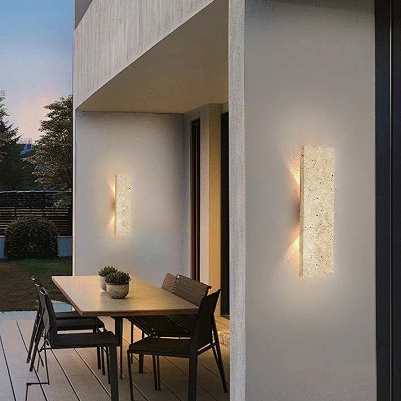 Milson Natural Stone LED Wall Light illuminated at dusk on an exterior wall