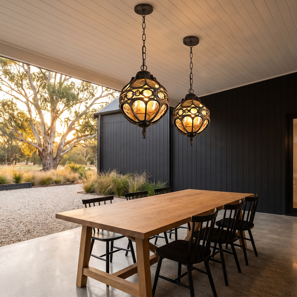 Two Olly vintage globe pendants in black over an oak table on a modern farmhouse verandah
