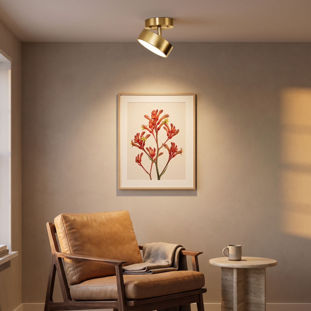 Onslow gold LED ceiling light tilted to spotlight wall art above a leather reading chair
