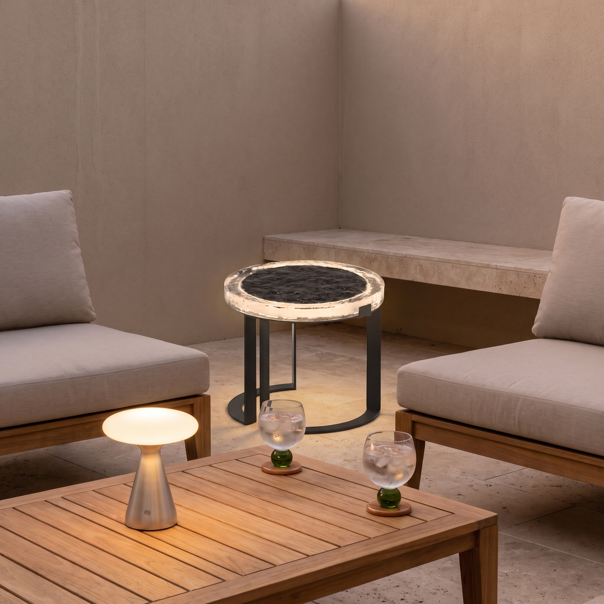 Kali solar table and Silvie cordless lamp glowing in a travertine courtyard with Ivy green glasses