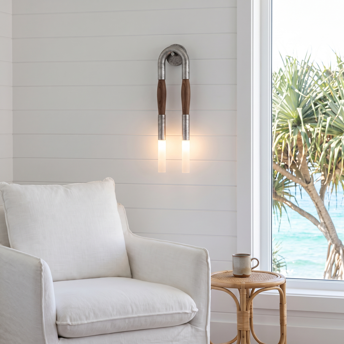 Salin nickel double wall sconce beside a white linen armchair in a coastal room