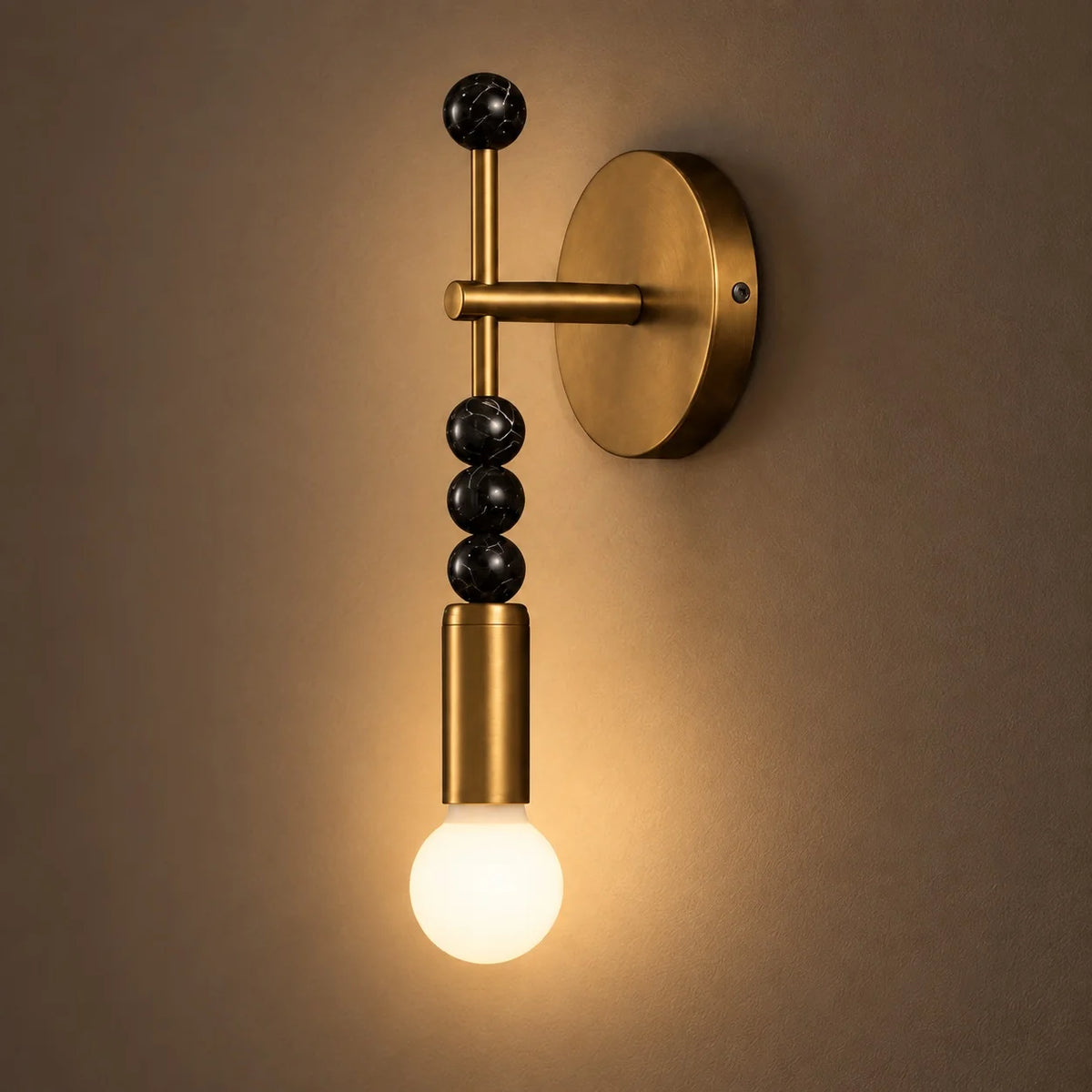 Sands antique brass wall sconce with black marble beads and a glowing globe