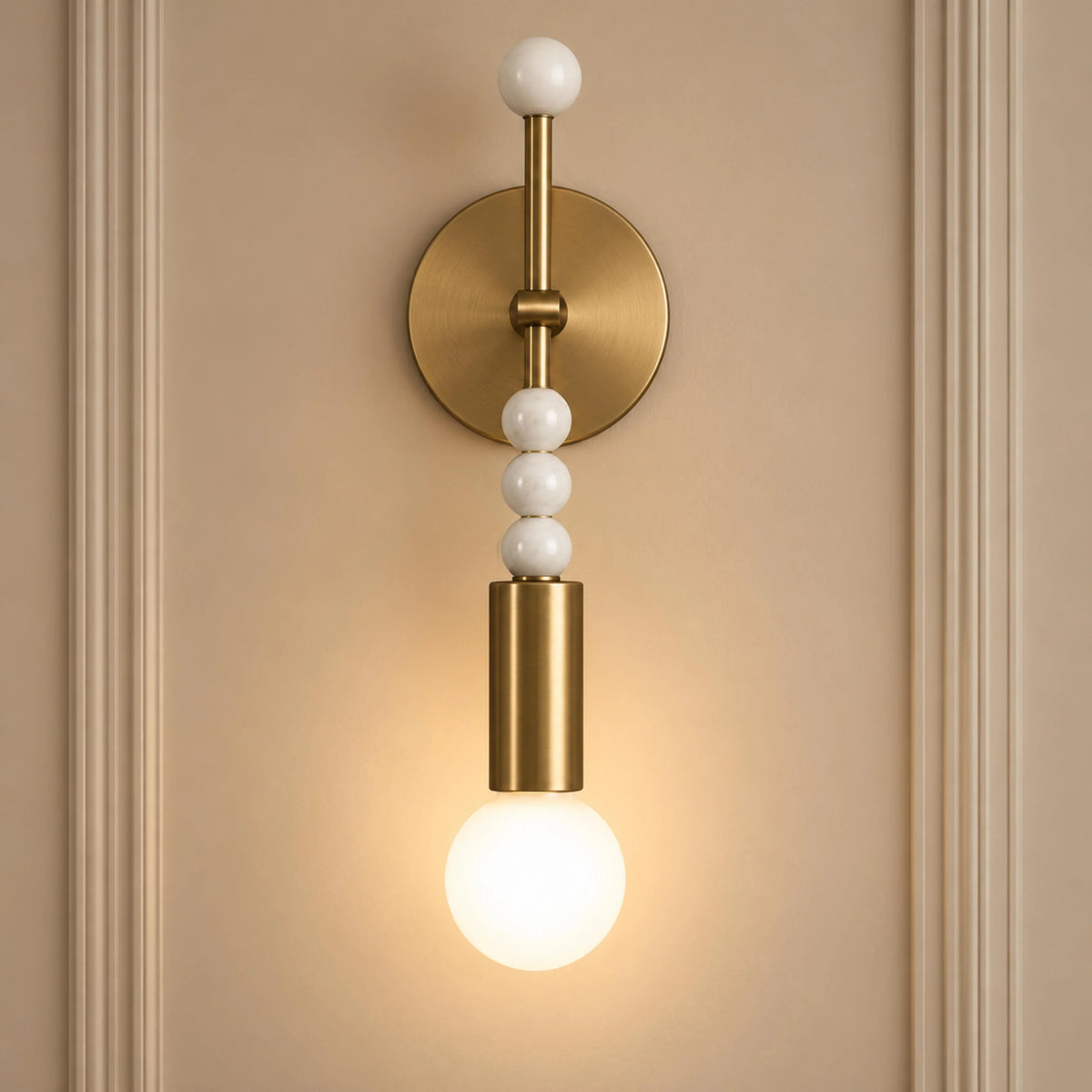Sands brass wall sconce with white marble beads on a cream panelled wall