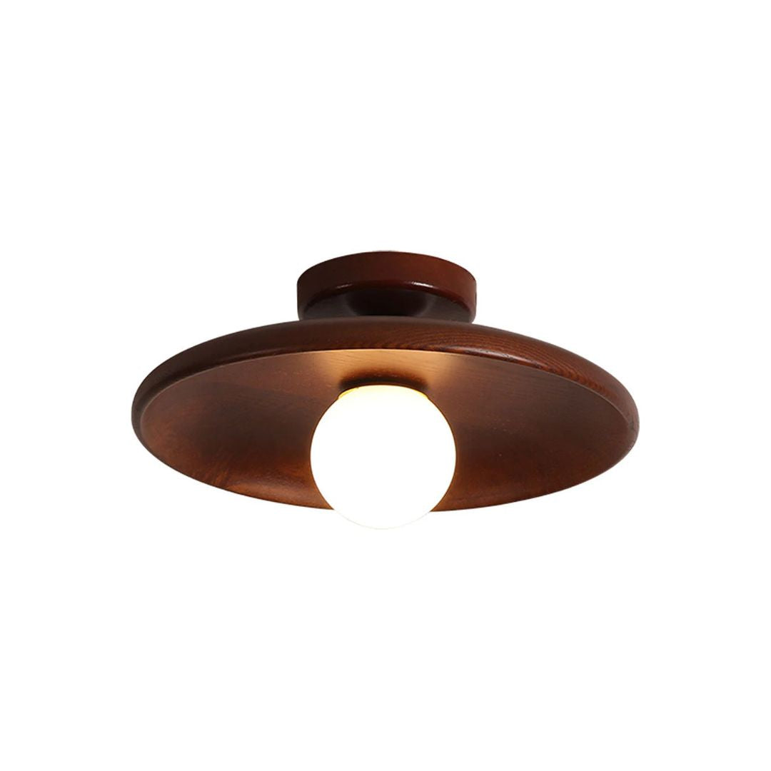Suma timber saucer ceiling light installed on a ceiling with its opal glass globe glowing warm