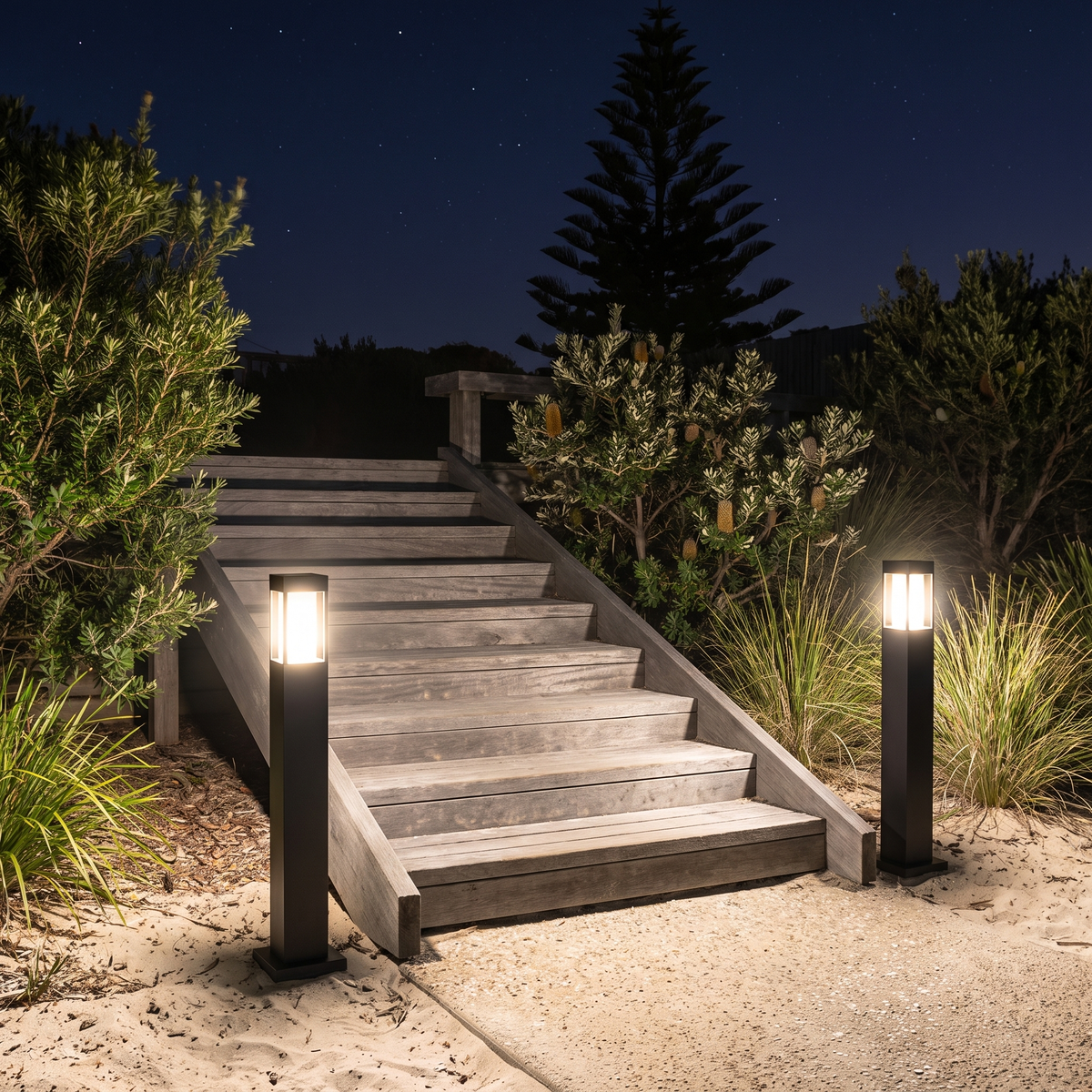Suraya Bollard Lights, large size, at the base of timber deck stairs in a coastal Australian backyard at night
