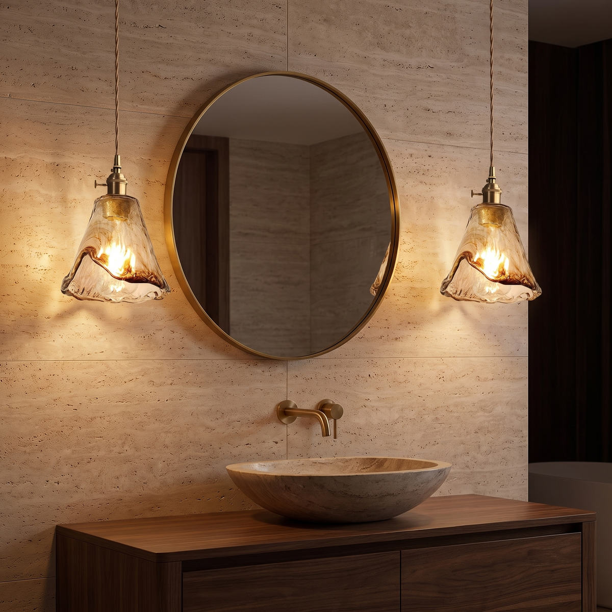 Two Tooky Model A amber pendants flanking a round brass mirror in a travertine bathroom