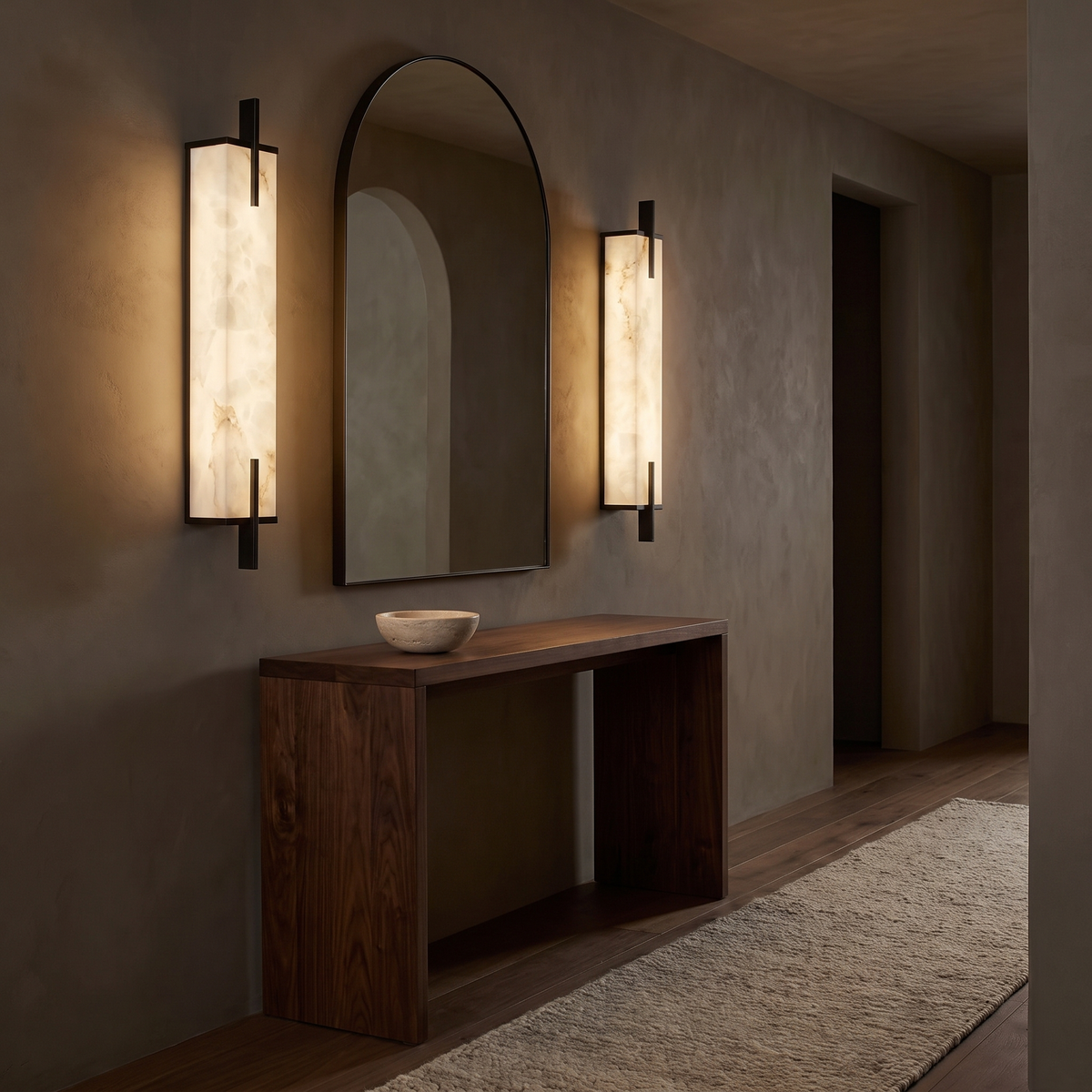 Pair of Tyla alabaster wall sconces with black end bars flanking an arched mirror in a hallway