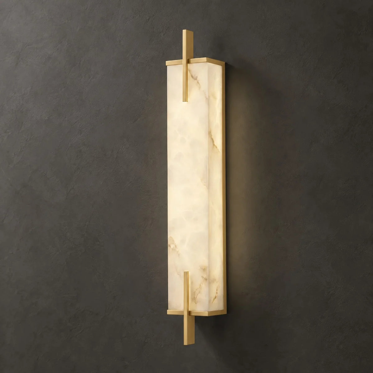 Tyla alabaster wall sconce in copper glowing against a dark charcoal plaster wall