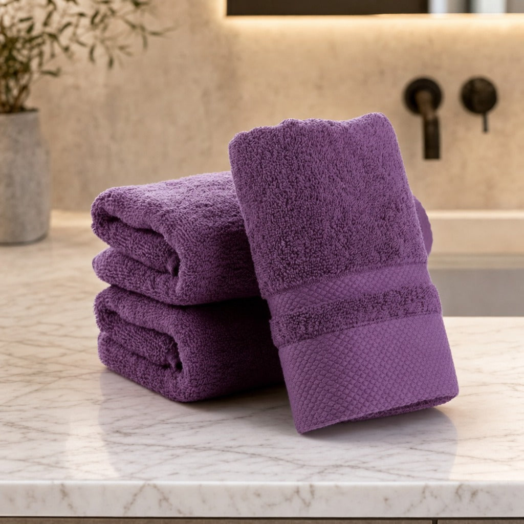 Velour striped cotton blend bath towels in purple folded on a marble bathroom vanity