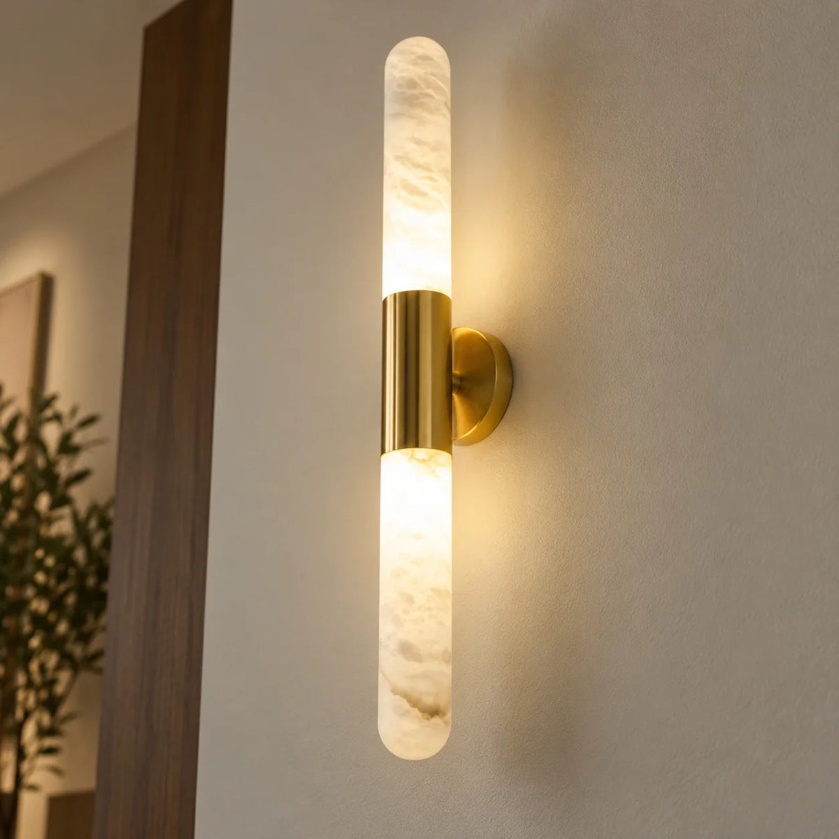 Waverly gold collar alabaster wall sconce glowing up and down beside a timber door frame
