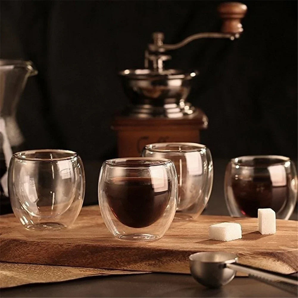 Zorin double-wall glass espresso cups on a timber board beside a vintage coffee grinder and sugar cubes